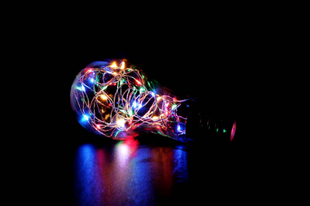 istock Colorful Fairy Light in a Light Bulb Shaped Glass Jar on Dark Background 948865368