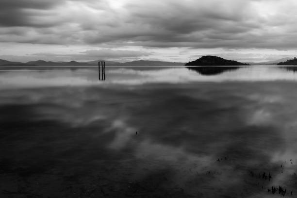 Lake shore at sunset with perfect reflections of clouds on water