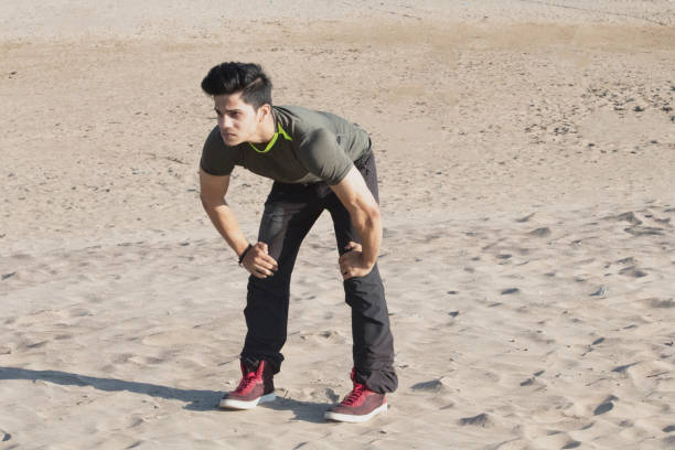 Tired man having rest after running hard on sand in the morning