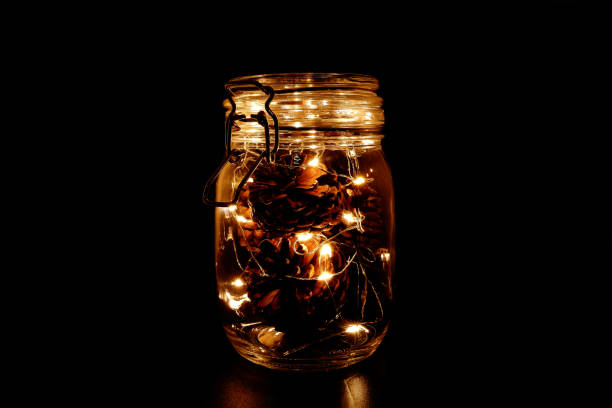 istock Pine Cones and Fairy Light in a Glass Jar on Dark Background 948868578