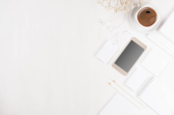 istock Modern stylish working place with blank white stationery, copy space, phone, cofee, flowers on soft white wood board. 948868674