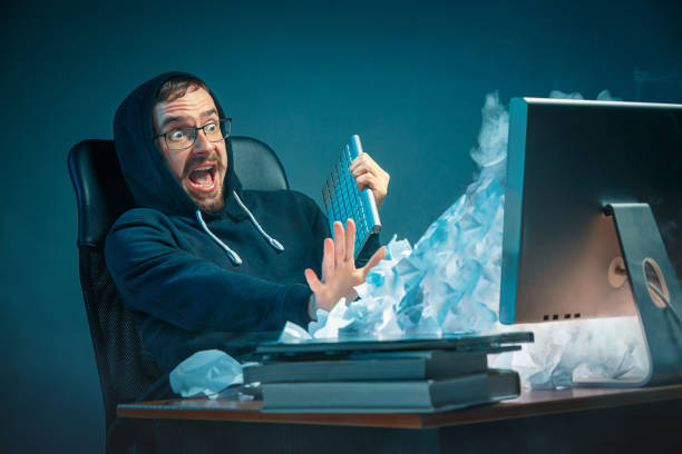istock Young stressed handsome businessman working at desk in modern office shouting at laptop screen and being angry about spam 948869026