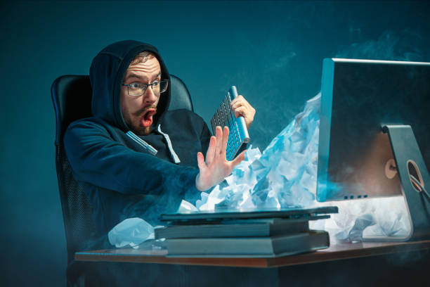 istock Young stressed handsome businessman working at desk in modern office shouting at laptop screen and being angry about spam 948874016