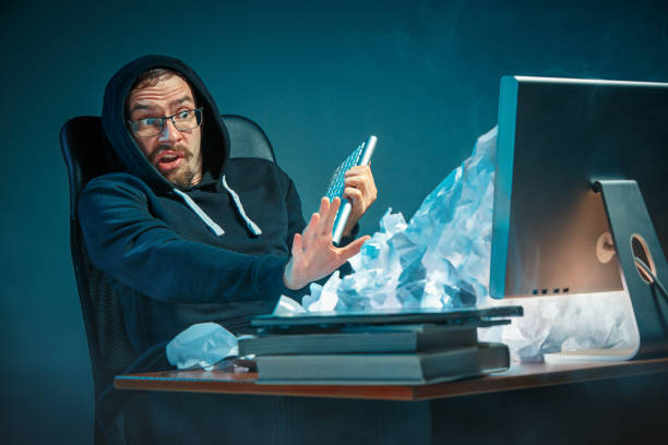 istock Young stressed handsome businessman working at desk in modern office shouting at laptop screen and being angry about spam 948874182