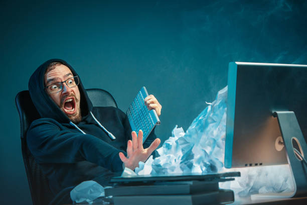 istock Young stressed handsome businessman working at desk in modern office shouting at laptop screen and being angry about spam 948874230