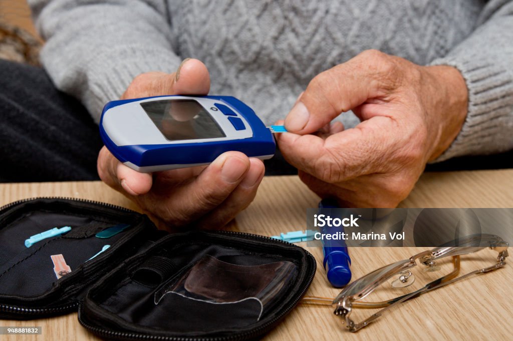 Concept diabetes in the elderly retired. Senior man with glucometer checking blood sugar level at home. Learn to use a glucometer Diabetes Stock Photo