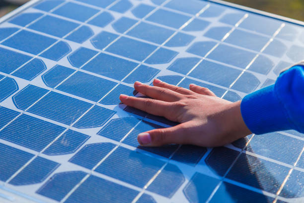 Human hand touching a solar panel Hand of the boy touching Solar cell in day light. solar panel manufacturing stock pictures, royalty-free photos & images