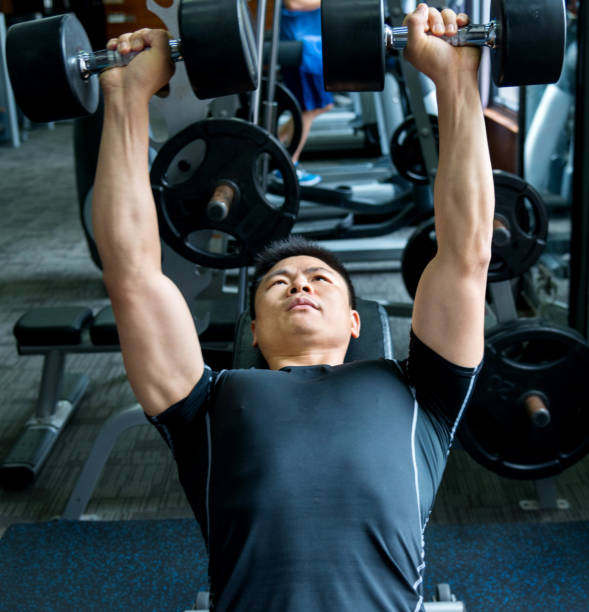 istock Man lying on exercise bench and lifting dumbbells 948883360