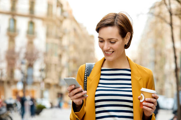 istock Woman texting while holding disposable cup in city 948887942
