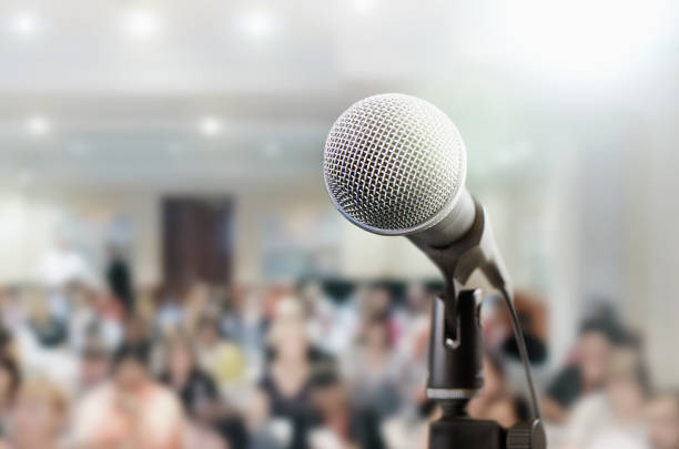 Microphone awaits public speaker at seminar Audience sits waiting for the speaker at a conference. The microphone is in the foreground. woman press conference stock pictures, royalty-free photos & images