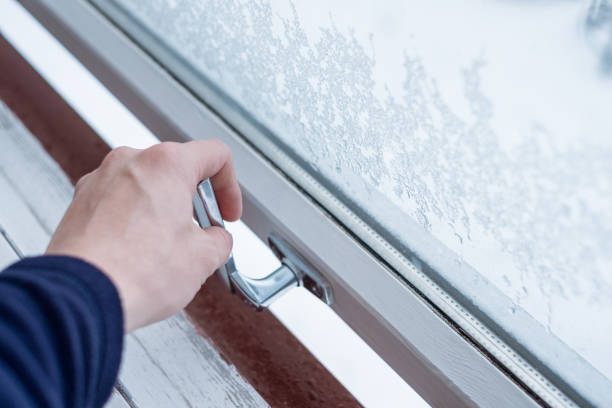 Photo of Hand opening lock window with ice flake in winter