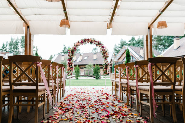 roses petals scattered on the road. wedding decor. wooden chairs in the backyard banquet area. arch for wedding ceremony a is decorated with flowers and greens, greenery. - material data sheets imagens e fotografias de stock