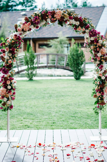 istock Arch for wedding ceremony a is decorated with pink hydrangeas, roses, white carnations flowers and greens, greenery in the backyard banquet area. Rose's petals scattered on the road. wedding decor. 948900140