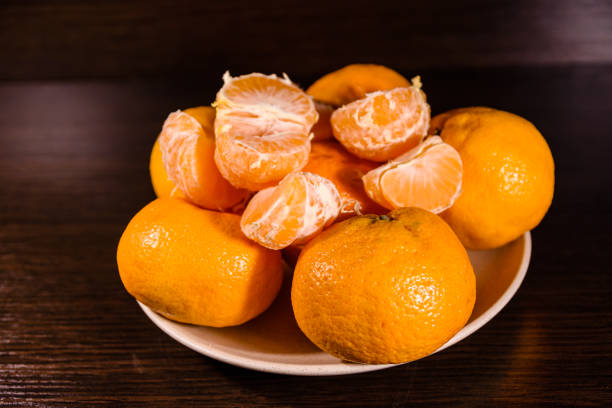 istock Plate with mandarins on a dark wooden table 948900534