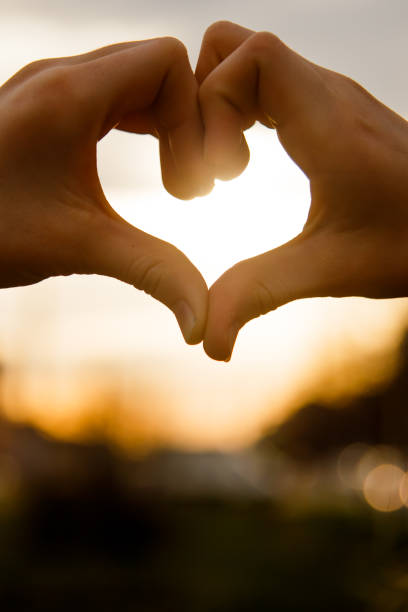 istock Hands in the shape of a heart glow at sunset 948920534