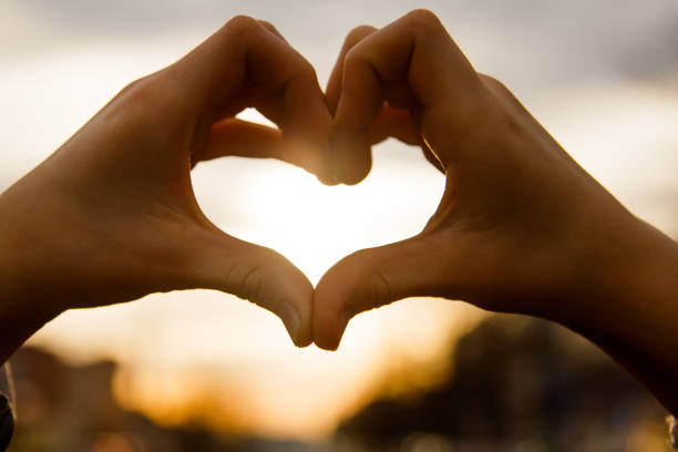 istock Hands in the shape of a heart glow at sunset 948920546