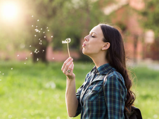 istock Woman blowing dandelion flower 948937704