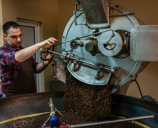 istock Coffee beans being poured out of a coffee roasting machine 948974118
