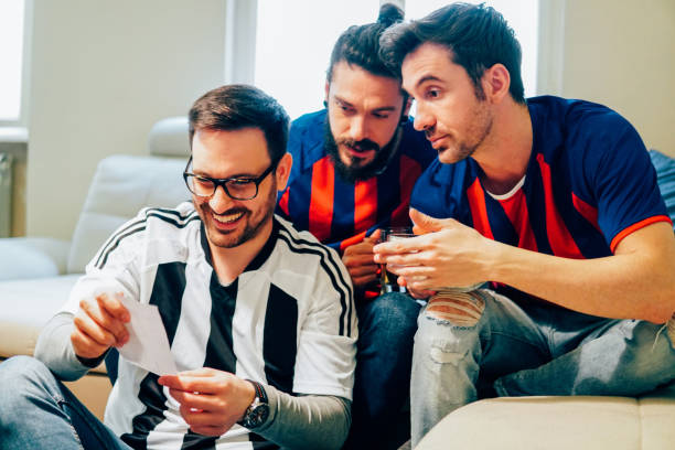Three men in football jerseys looking at betting slip
