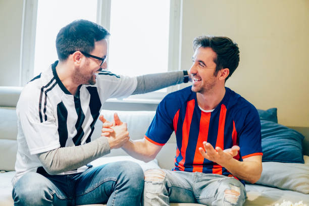 istock Happy male soccer supporters shaking hands and smiling 948990110