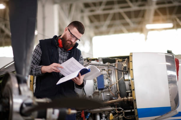 Aircraft mechanic in the hangar Male aircraft engineer in the hangar reading instruction manual before repairing private jet airplane. instruction manual photos stock pictures, royalty-free photos & images