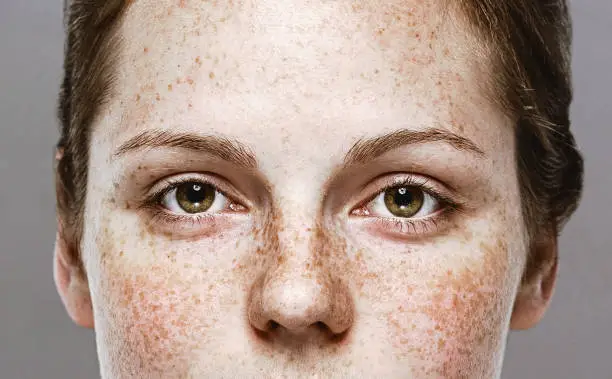 Eyes woman Young beautiful freckles woman face portrait with healthy skin. Studio shot. Isolated on gray.