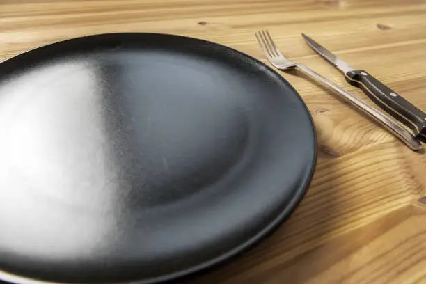 empty plate, knife and fork on an aged pine wood table. Background with copy space