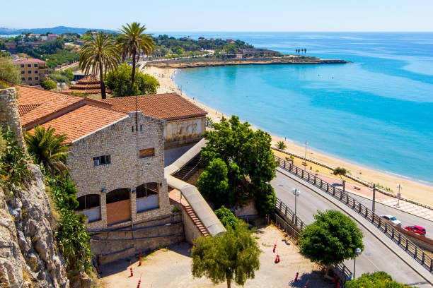 Panoramic view of coast of Tarragona in sunny day, Catalunya, Spain. Landscape  coastline of Costa Dorada surroundings of Salou - sea, beach, palms and tiled roofs of houses, view of with Mediterranean Balcony, Tarragona, Catalunya, Spain cambrils stock pictures, royalty-free photos & images