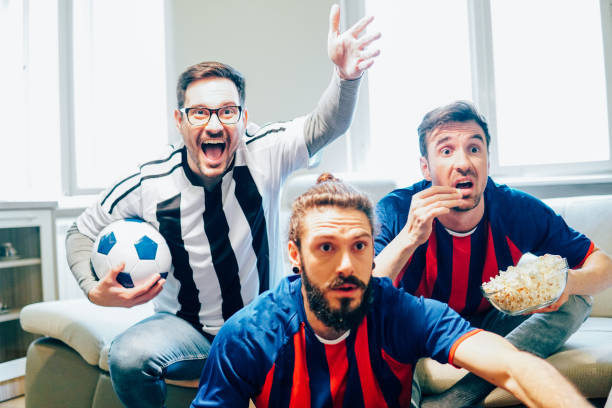 istock Anxious men watching soccer game and eating popcorn 949032170