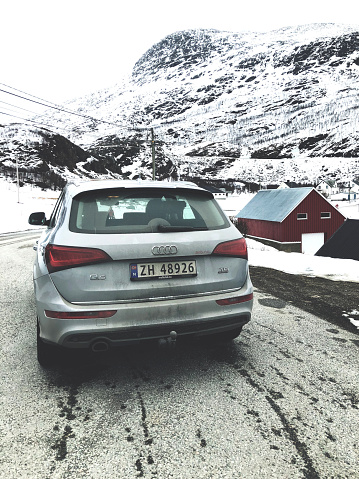 Tromso, Norway - April 14th, 2018: Car Audi Q5 parked on a side of the road close to a Lake in Northern side of Norway. On the background are visible the mountains with snow. The car is shot from a rear point of view