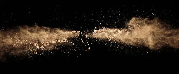 Photo of Abstract colored brown powder explosion isolated on black background.