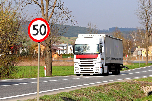 Road sign on the highway. safety of traffic. Motor transportation of passengers and cargoes. Modern cars. A large truck is moving along the road.