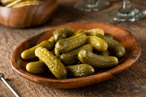 Baby Dill Pickles A bowl of baby dill pickles on a rustic wood table top. pickle stock pictures, royalty-free photos & images