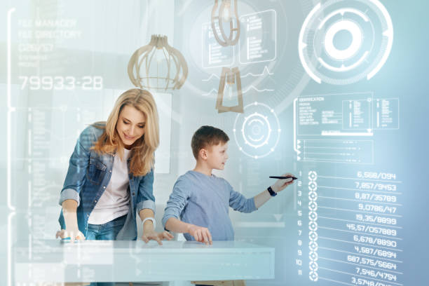 istock Calm boy holding a stylus while his smiling mother working near 949071812