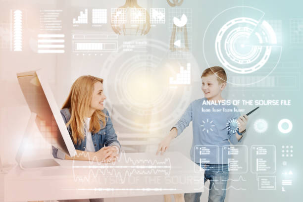 istock Emotional boy holding a stylus while talking to a smiling teacher 949072140