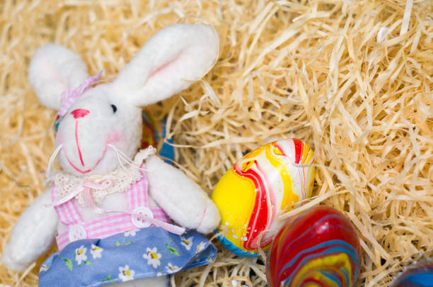 istock Concept of Easter, plush Easter bunny on straw background with decorated. 949077826