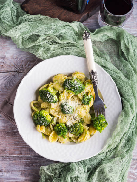 Orecchiette pasta with broccoli in white dish on wooden table. Easy recipe for lunch.