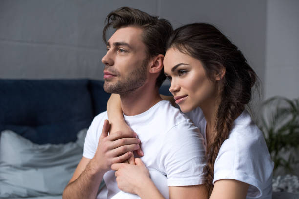 istock Young attractive couple hugging in bedroom and looking away 949078352
