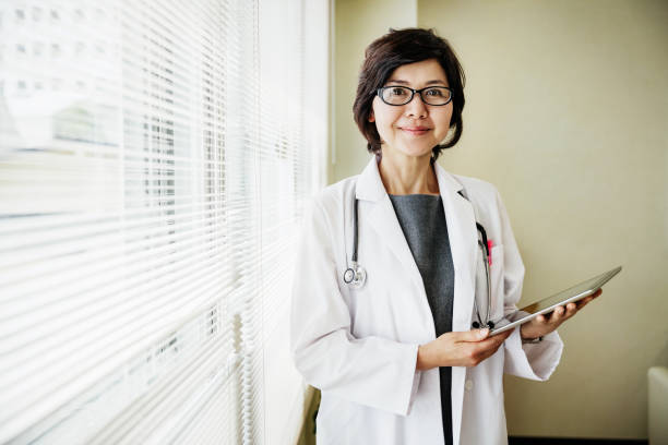 Portrait of Doctor Holding Clipboard A portrait of a Japanese doctor holding a clipboard and smiling. japanese female doctor stock pictures, royalty-free photos & images