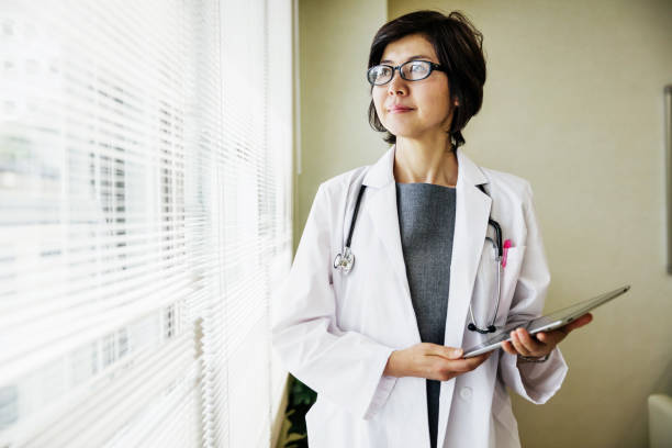 Portrait Of Japanese Doctor A portrait of a Japanese doctor holding a clipboard. japanese female doctor stock pictures, royalty-free photos & images