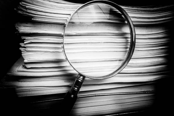 Magnify glass inspects paper documents Handheld Magnify glass inspects paper documents criminal investigation photos stock pictures, royalty-free photos & images