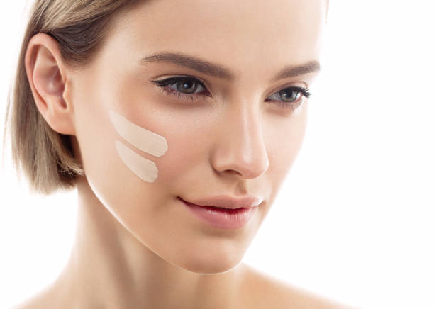 Skin tone cream lines on woman face. Beautiful woman portrait beauty skin healthy and perfect makeup Skin tone cream lines on woman face. Beautiful woman portrait beauty skin healthy and perfect makeup. Studio shot. Isolated on white. liquid foundation face stock pictures, royalty-free photos & images