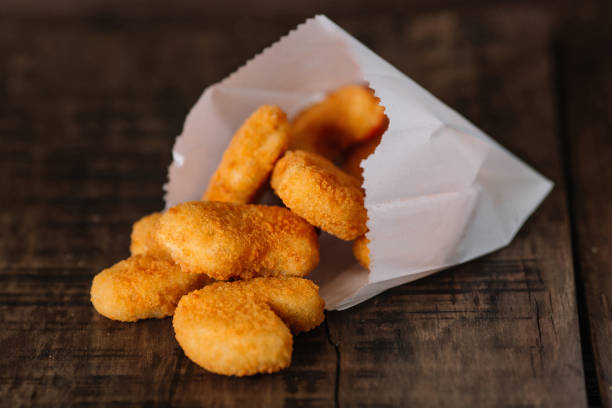istock Fried chicken nuggets in a paper bag on wood background 949106848