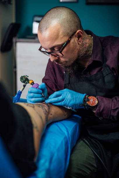 istock Expert tattooing female customer's lap 949107370