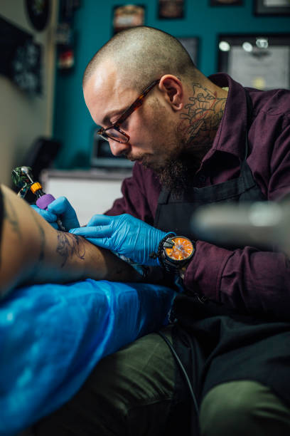 istock Expert tattooing female customer's lap 949107508