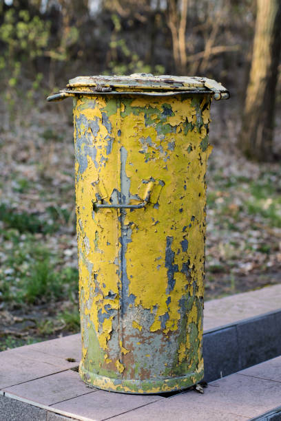 istock An old garbage bin. Waste trash cans set in a park between trees on a concrete foundation. Season of the spring. 949114076