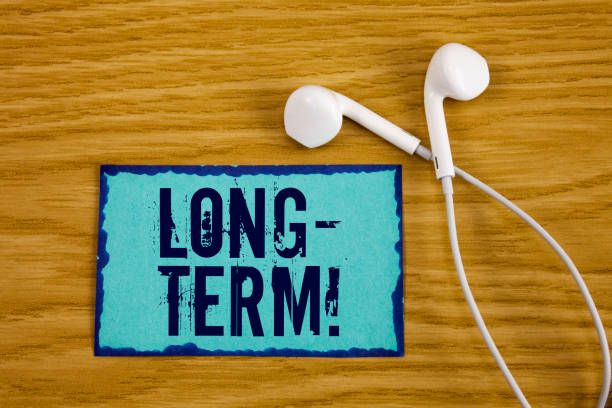 istock Writing note showing  Long-Term Motivational Call. Business photo showcasing Occurring over large period of time Future plans written on Sticky Note Paper on wooden background Handsfree next to it. 949117948