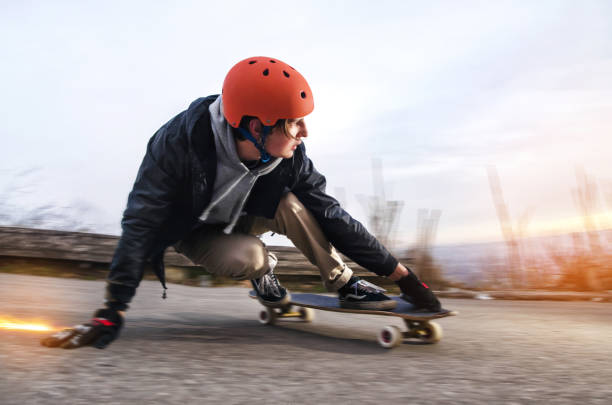 junger mann im helm wird schieben, schieben mit funken auf einem longboard auf dem asphalt - longboard skating stock-fotos und bilder