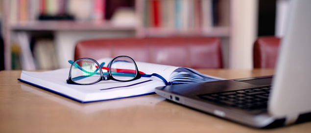 Office tools for school project: laptop, book, eyeglasses.