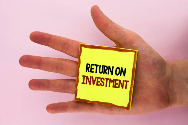 istock Handwriting text writing Return On Investment. Concept meaning Performance Measure Evaluation of a Business Efficiency written on Sticky Note Paper placed on the Hand on the plain background. 949123756